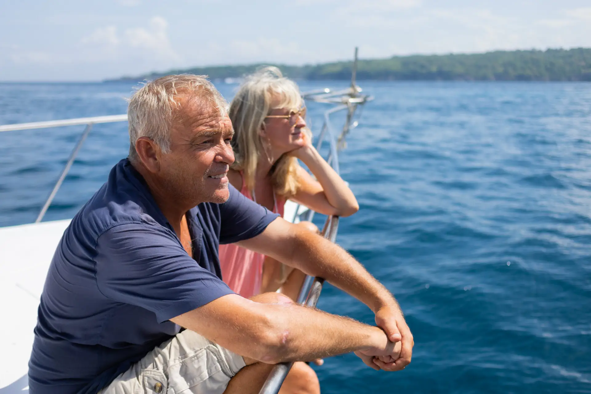 Older couple sitting on sailboat looking out at open water
